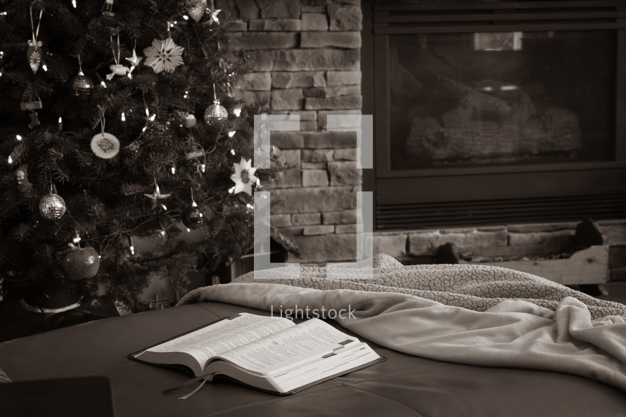 open bible by Christmas tree and fireplace
