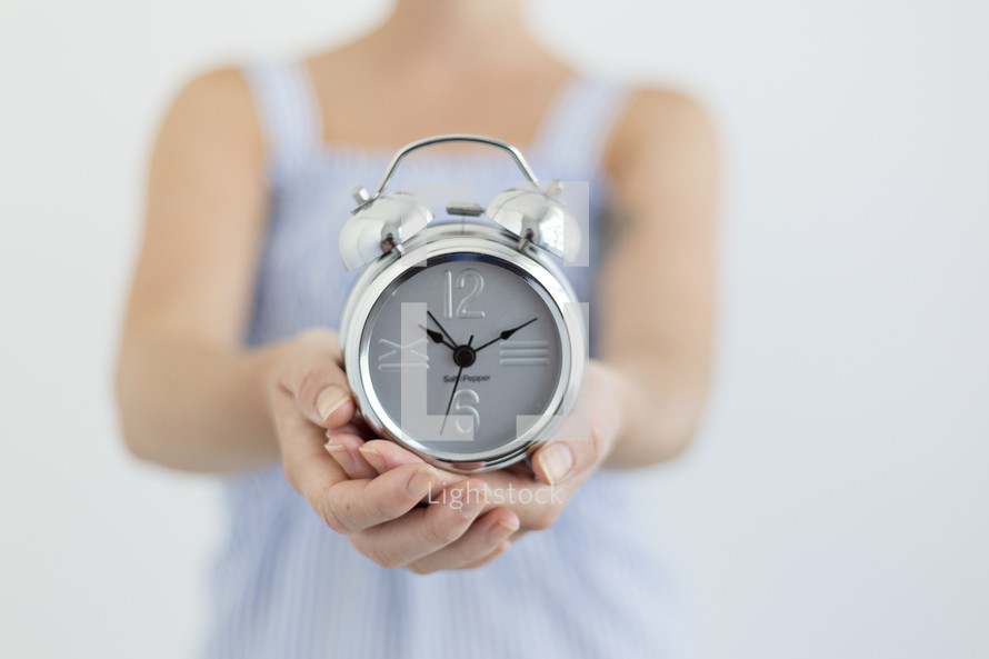 woman holding an alarm clock in cupped hands 