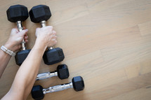 Woman's hands picking up dumbbells