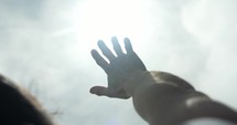 Bright light shines on hand of man raising his hand worshipping. Young man in worship, prayer and faith.