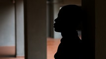 silhouette of a young man leaning against a wall 