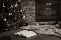 open bible by Christmas tree and fireplace