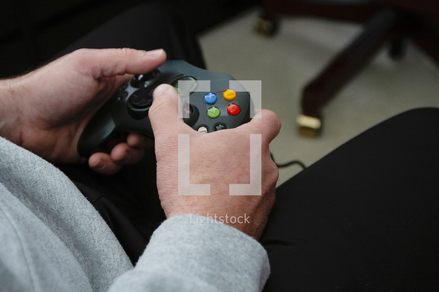 man's hands holding a video game controller 