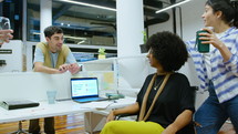 Young Coworkers Chatting Over Cubicle Wall and Laughing in the Office
