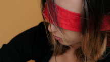 Woman with a red blindfold covering her eyes.