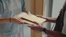 Male courier delivering express mail to female client at home, giving her document for signing, then leaving. Medium close-up, tilt-up shot
