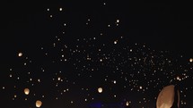 Hundreds of Chinese lanterns floating in the night sky.