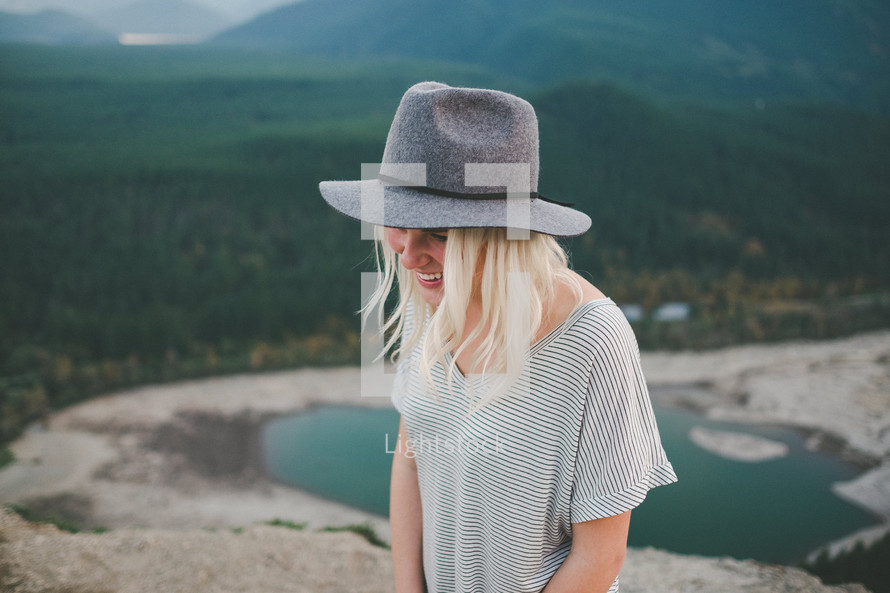 a woman in a hat with lake in background 
