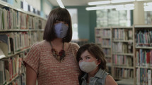 mother and daughter in a library wearing face masks 