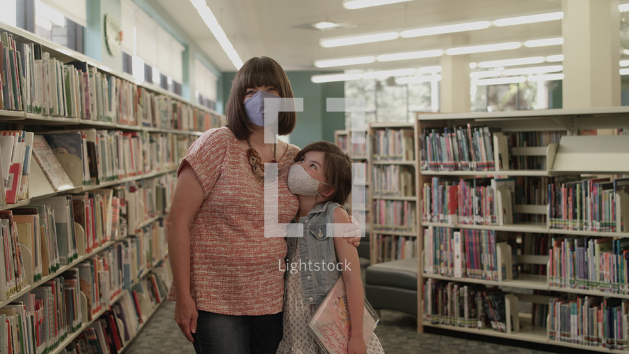 a mother and daughter wearing face masks at a library 