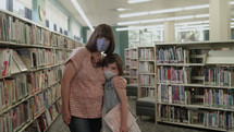 mother and daughter a library wearing face masks 