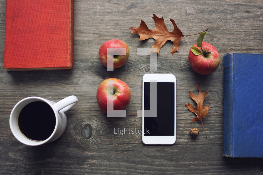 vintage books, fall leaves, iPhone, apples, on wood background 
