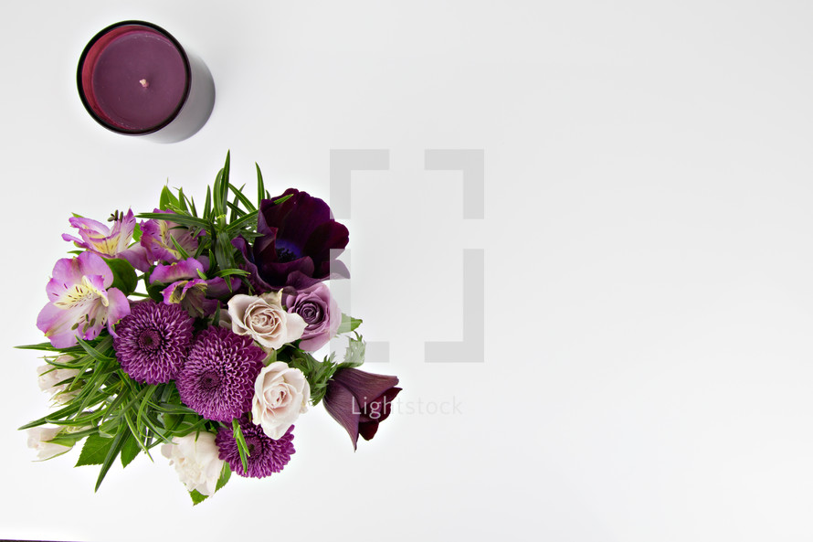 purple flower arrangement and candle on a white background 