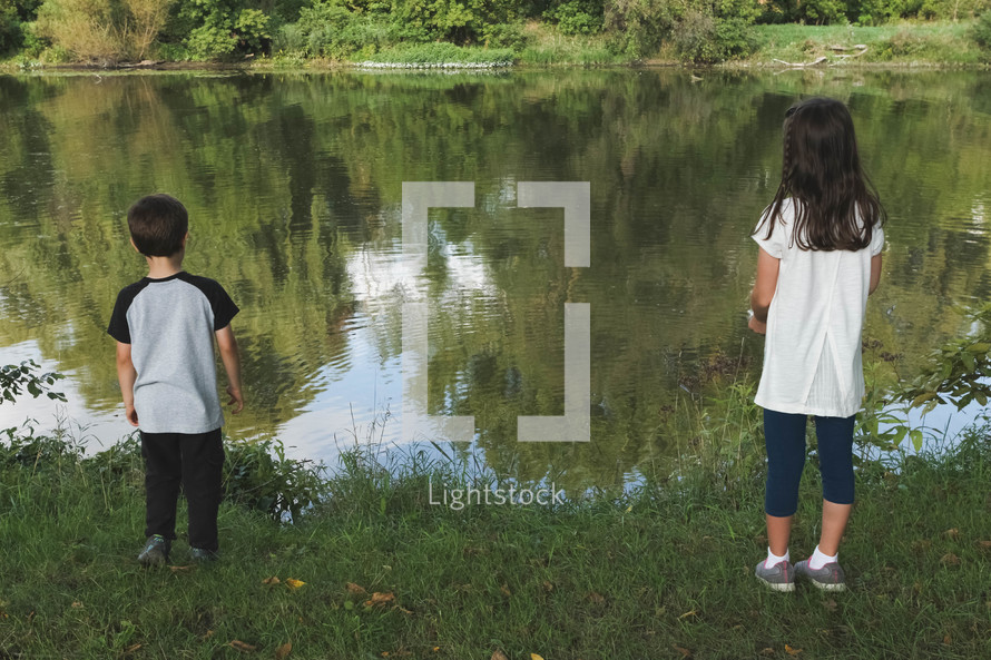 children standing in front of a pond 