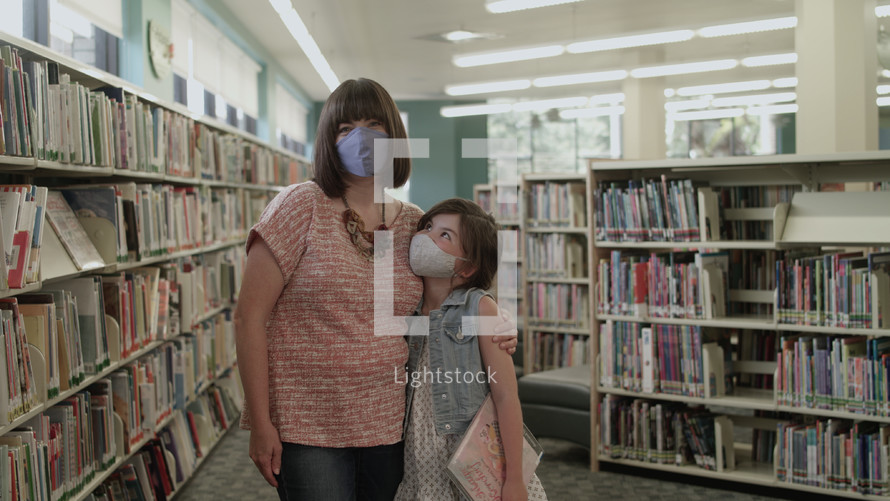 mother and daughter at a library wearing face masks 