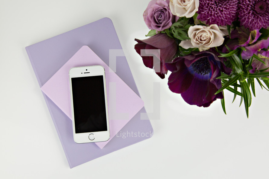 iPhone, journals, purple flower arrangement on a table 