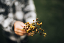 a boy holding dried picked flowers 