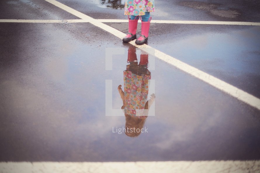 a child splashing in a puddle in rain boots 