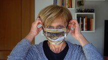 an older woman putting on a face mask 