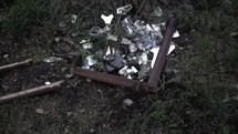 Shards of broken glass from shattered mirror laying in grass on ground in cinematic slow motion.