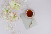 flower petals, journal, pen, and cup of tea 