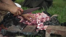The hand of a middle eastern, Muslim man with knife cutting sheep meat preparing for Islamic religious holiday Eid Al Adha or Eid Al Fitr in cinematic slow motion.