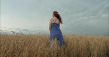 Closeup of a young woman worshipping, contemplating, praying outside in nature in a wheat field.