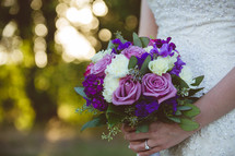 a bride holding a bouquet of purple roses 