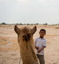 boy leading a camel in India 
