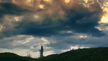 A Pilgrim silhouette on a hill with dramatic clouds
