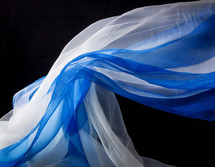 draped woven fabrics in blue and white against a black background