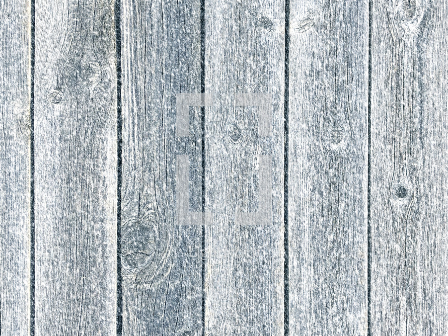 Weathered fence panel in snowfall with blue tint