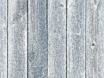 Weathered fence panel in snowfall with blue tint