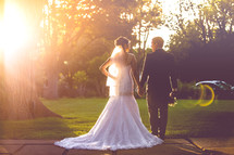 portrait of a bride and groom standing under bright sunlight 
