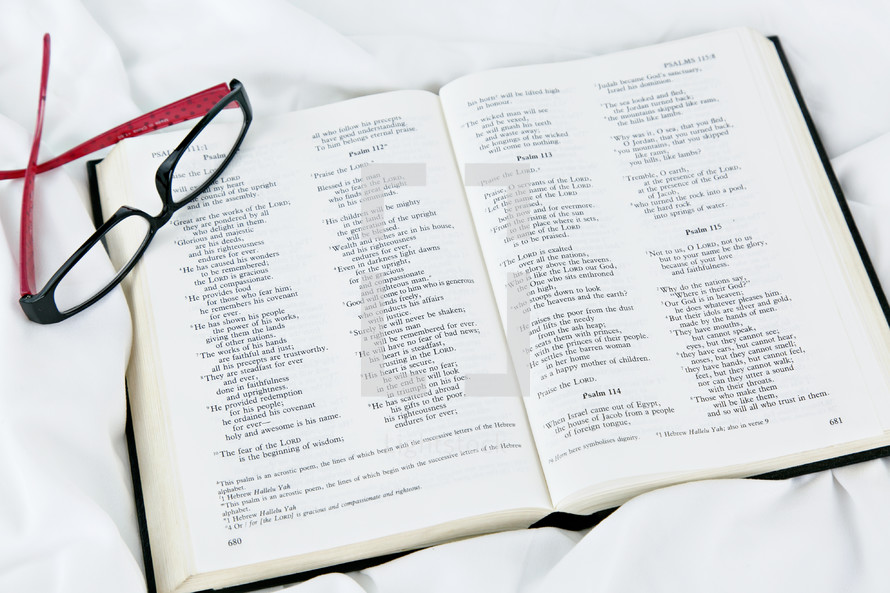 reading glasses on a Bible on a bed 
