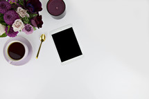 purple flower arrangement, spoon, tea, cup, tablet, and candle on a white background 