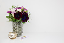 purple flower arrangement, candle, and clips on a white table 