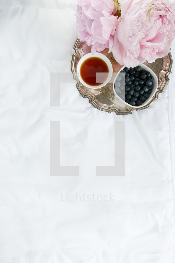 silver tray, peonies, bowl of blueberries, and cup of tea 