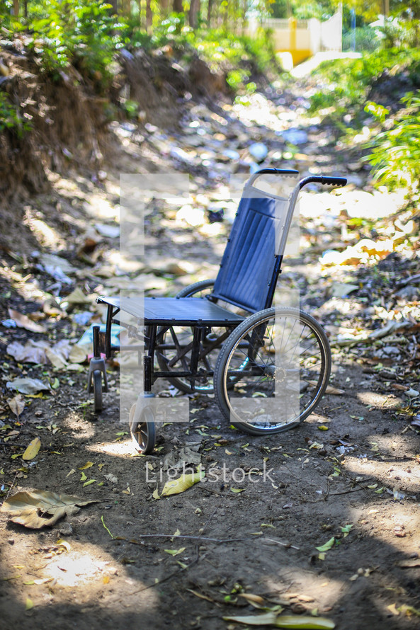 Old wheelchair in a dirt path 