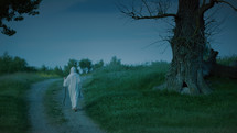 Christ as the Eternal Pilgrim walks slowly along the country road in the evening.
