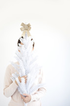 a woman holding a mini white Christmas tree