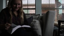 Woman sitting on the sofa, reading the Bible.
