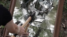 Angry teenage boy with self hate breaks a mirror with an axe in cinematic slow motion.