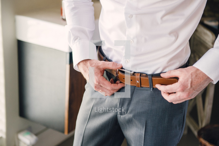 a groom adjusting his belt 