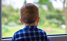little boy looking out a window, anonymous person