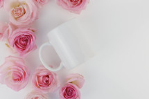 pink roses and coffee mug on a white background 