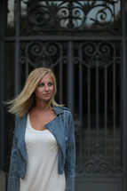 blonde woman with her hair blowing standing in front of a gate