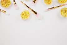 gold makeup brushes and gold flowers on pink 