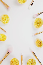 border of makeup brushes and yellow flowers 