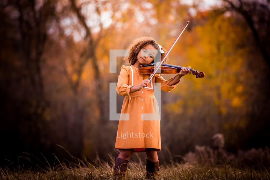 a girl playing a violin outdoors 